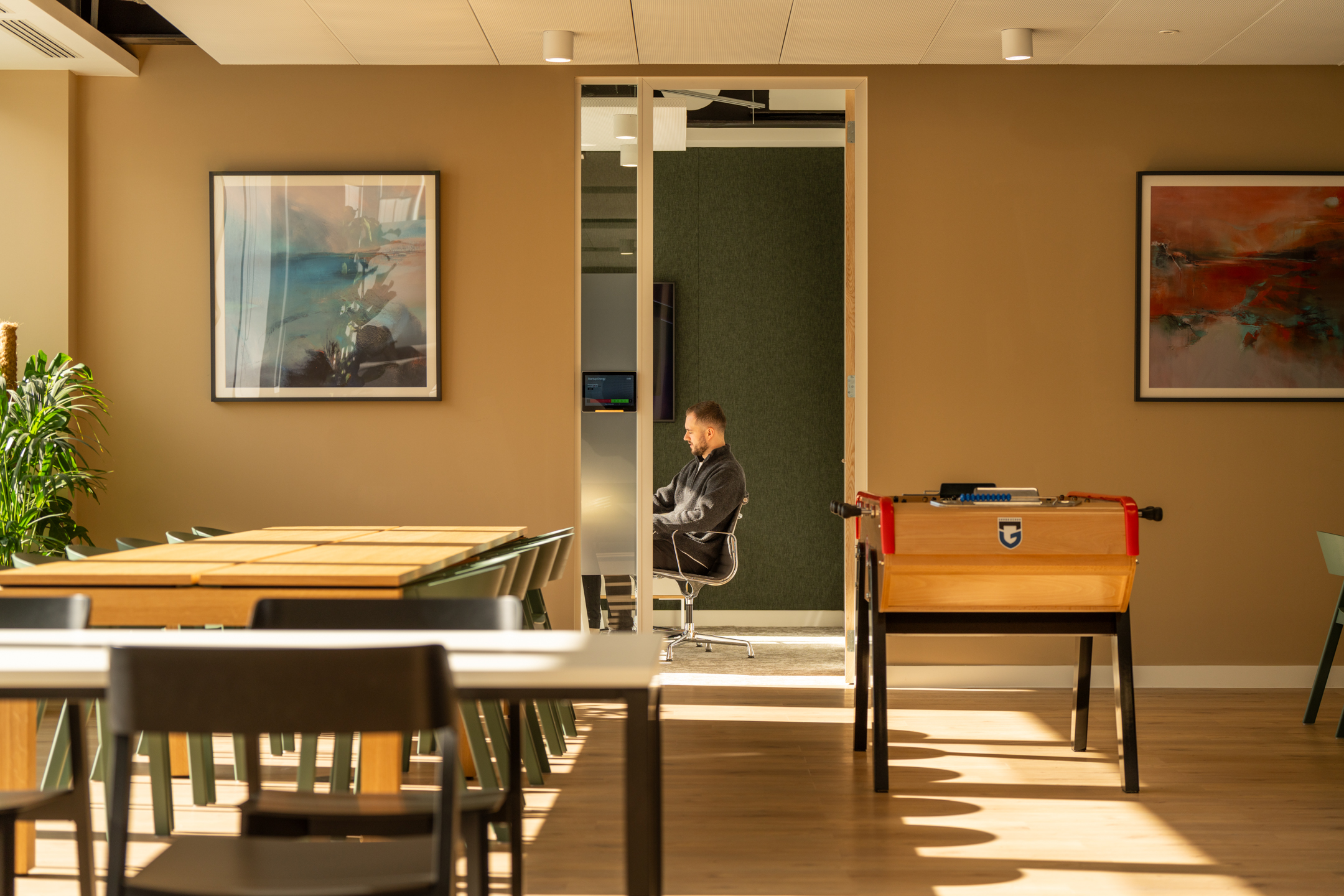 Shionogi’s social workspace with Japandi-style chairs, natural wood tables and a foosball table, blending informal calm with focused functionality.