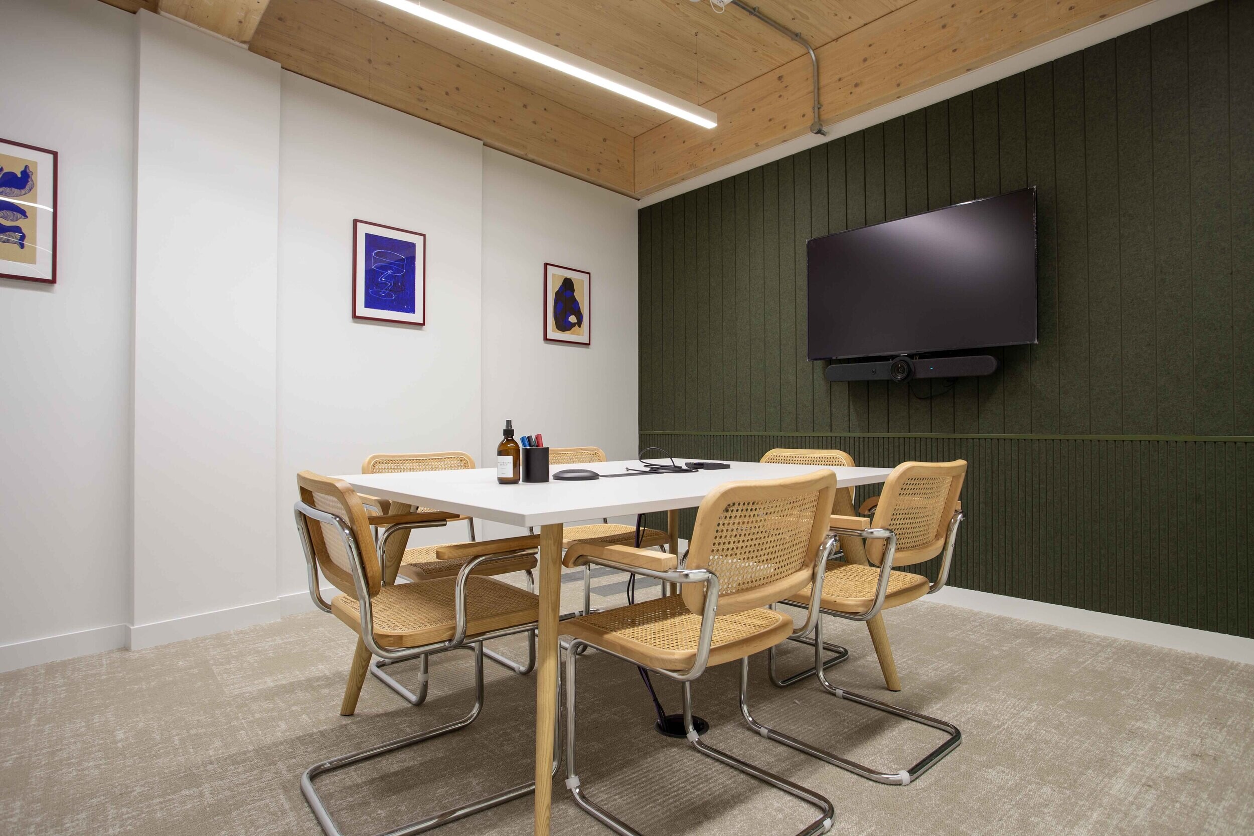 Techspace meeting room with white table and cane chairs styled against the signature gin green wall finish