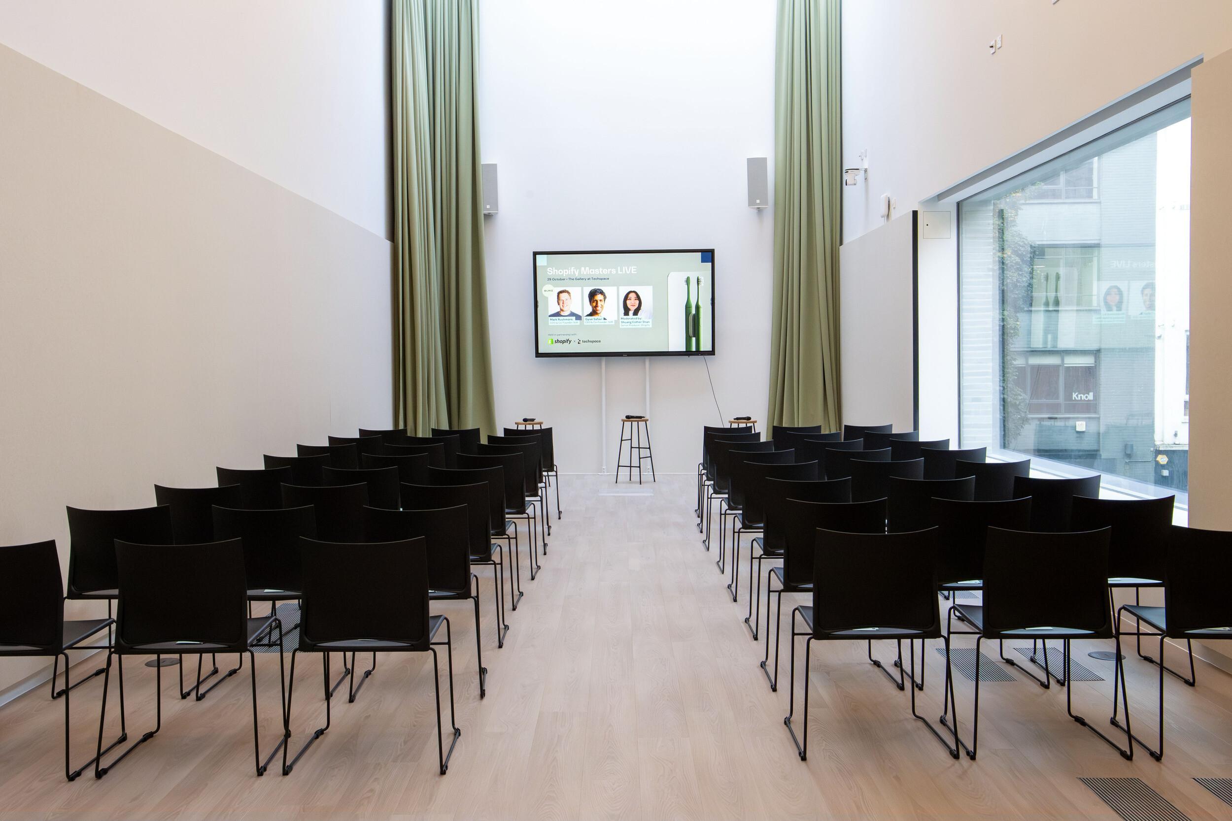Techspace event space with rows of black chairs and large screen setup for talks panels and community gatherings