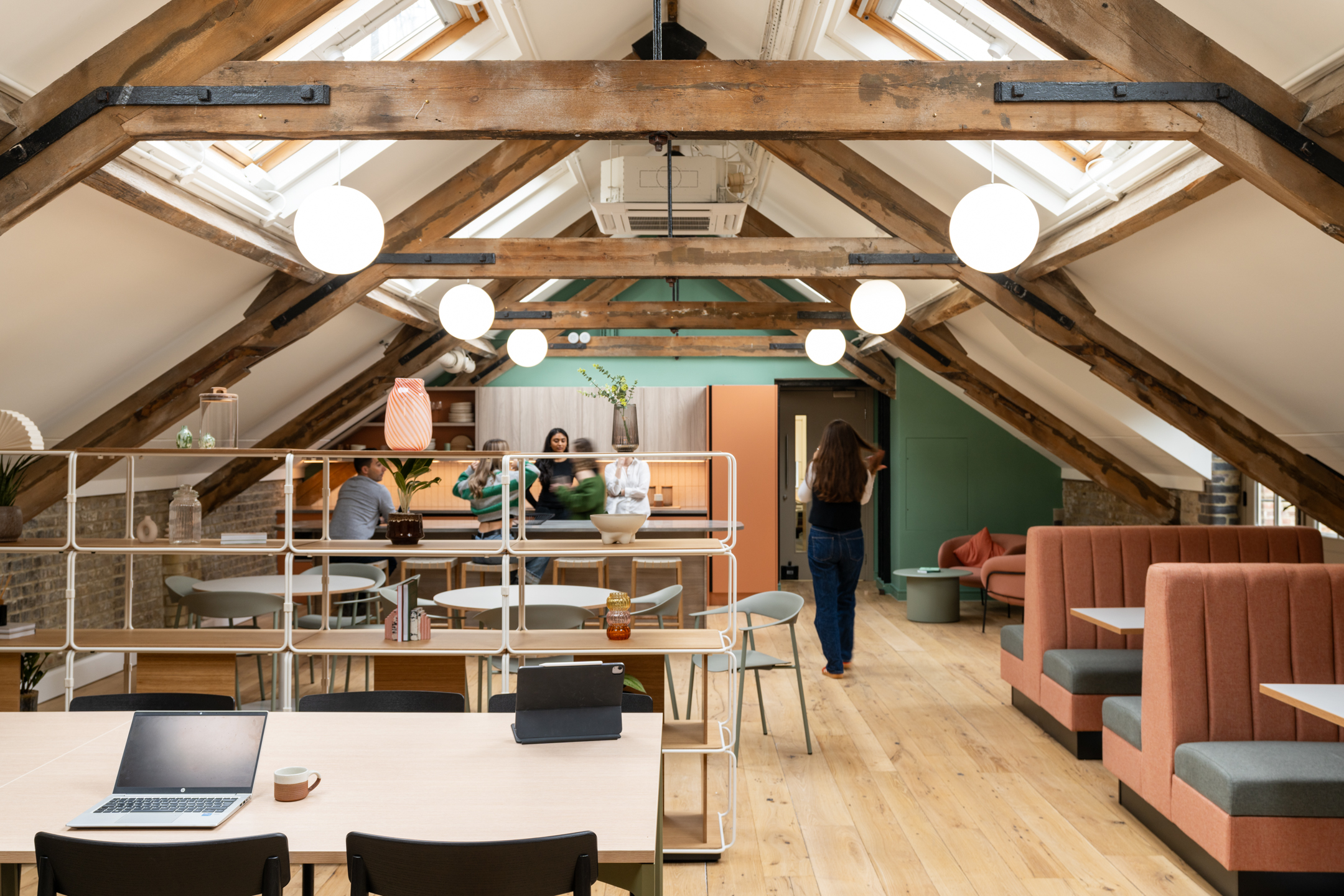 Open-plan layout at The Varnish Works with coral booths, playful shelving and timber beams blending vintage character with soft modern styling