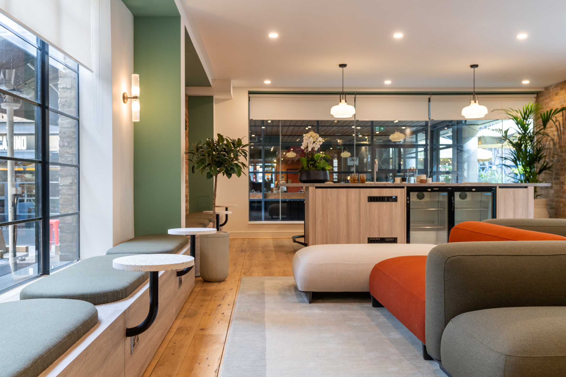Curved seating in olive and rust tones shapes the relaxed lounge at The Varnish Works, styled with terrazzo tables, timber floors and soft lighting