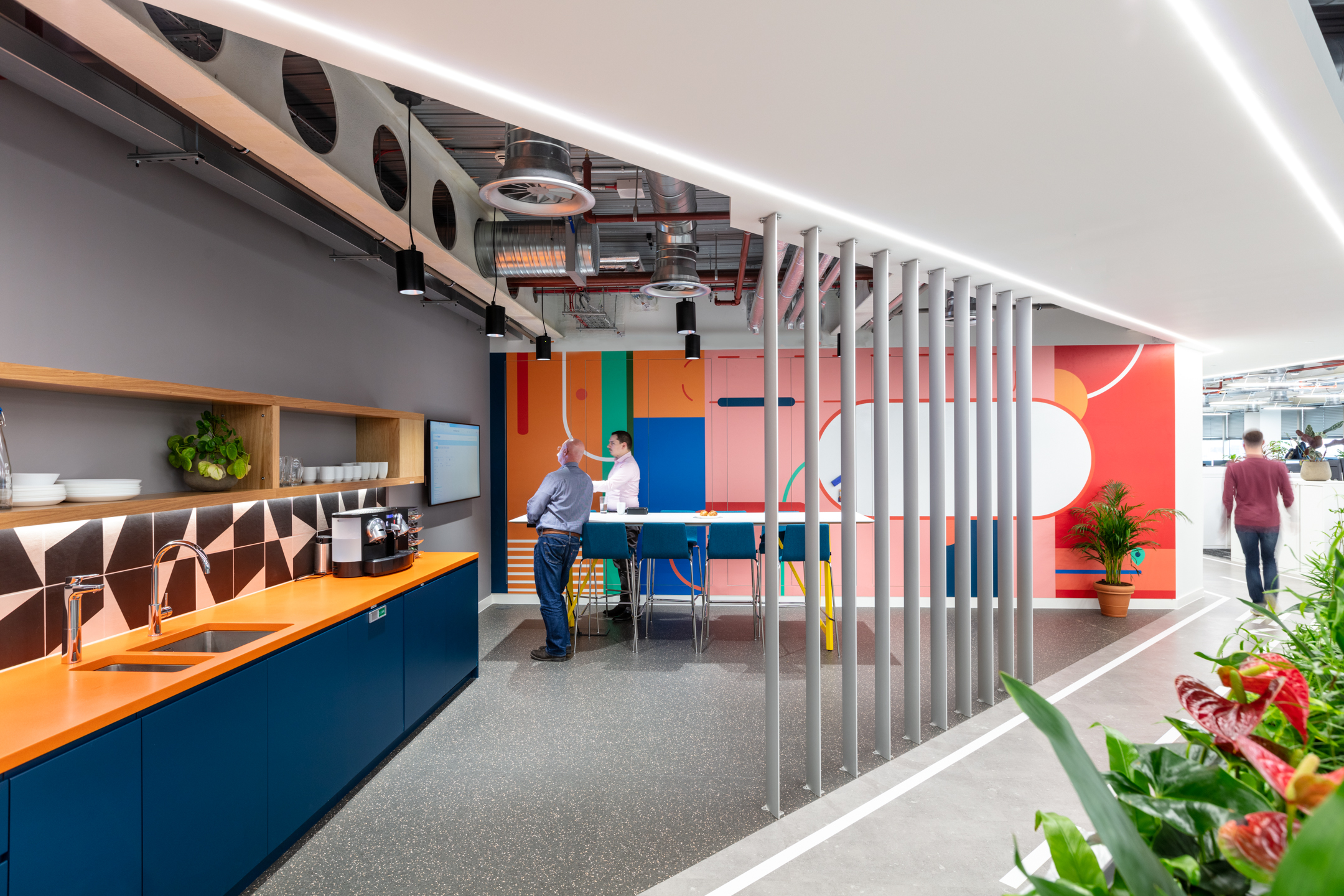 Travelfusion teapoint with Platfform-supplied high stools and shared tables, designed to encourage quick catchups against a backdrop of vibrant wall graphics.