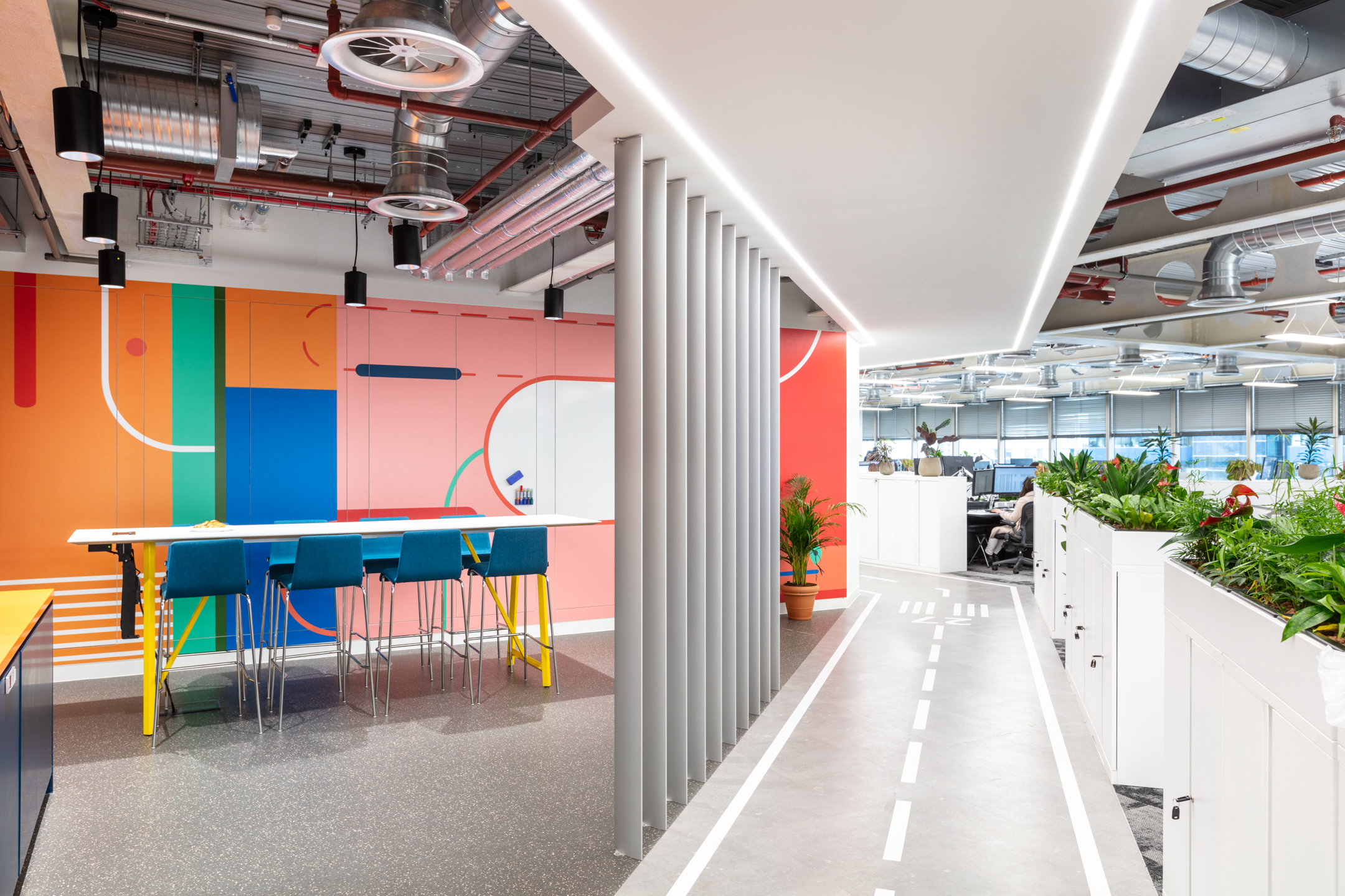 Travelfusion open-plan office with vibrant breakout furniture by Platfform, including high stools and shared tables set alongside a runway-themed walkway.