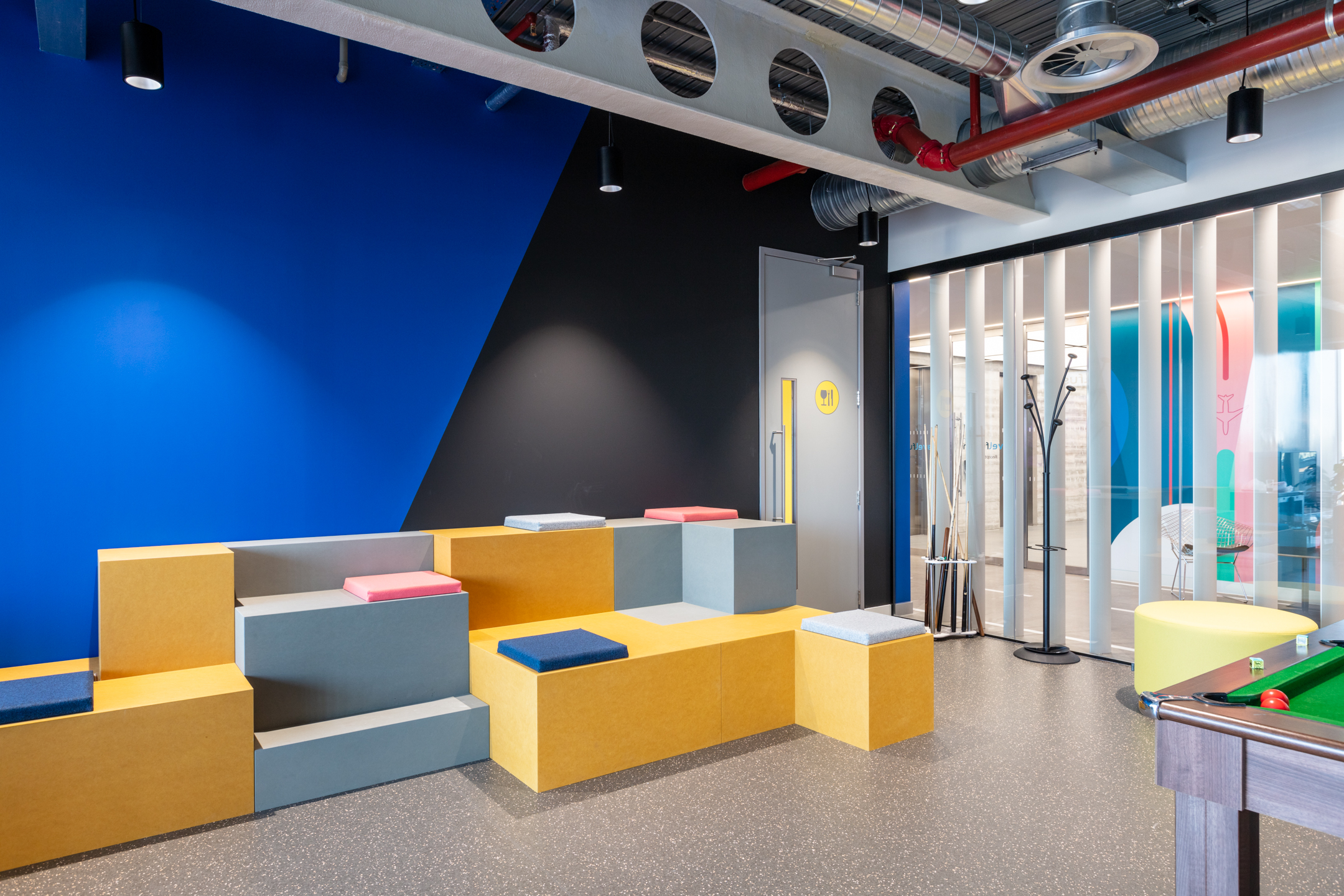 Travelfusion tiered seating area with vibrant modular blocks and soft cushions, curated by Platfform to support informal gatherings and team socials.