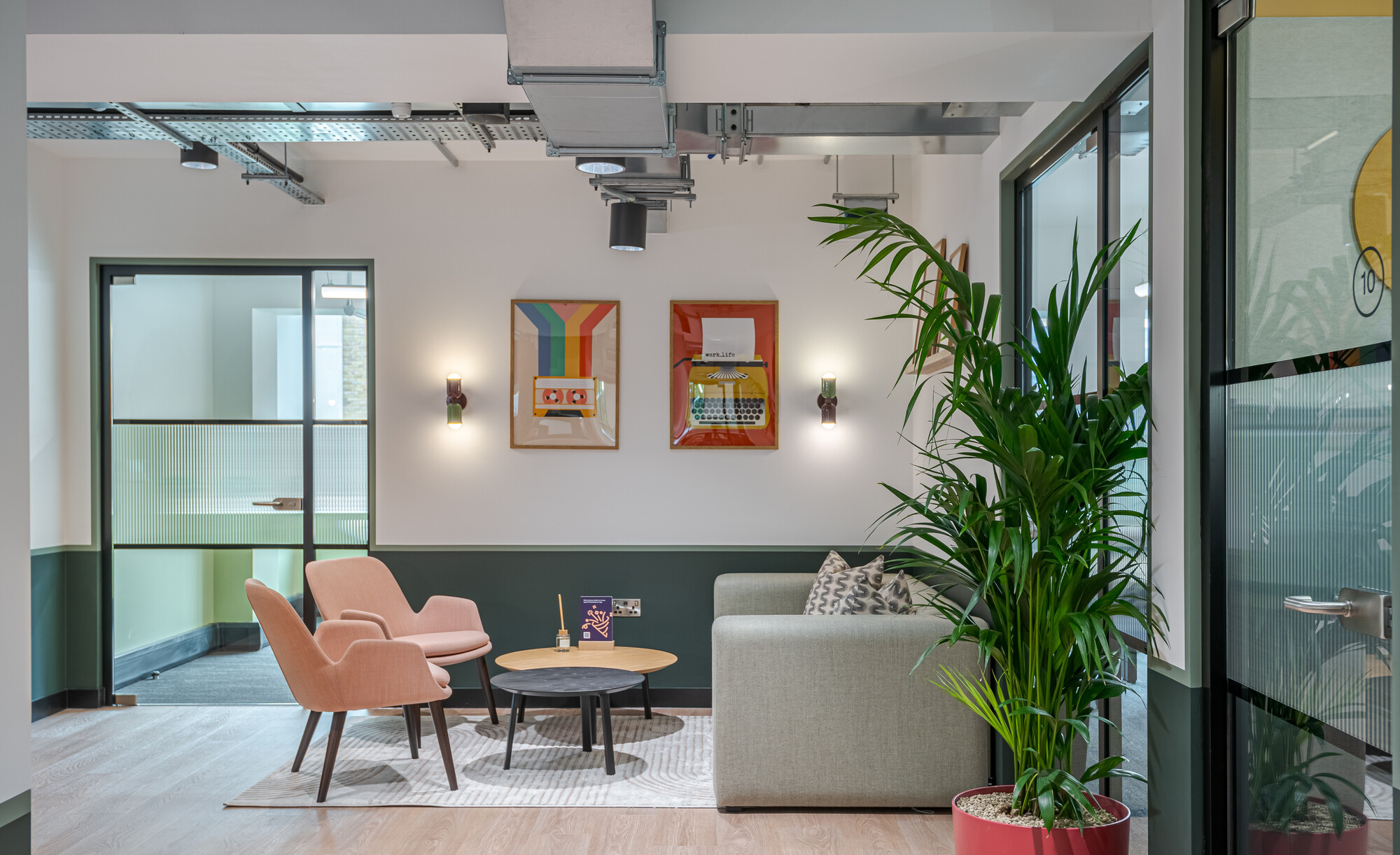 Work.Life Typewriter lounge with soft seating and framed retro prints, styled with greenery and furniture that balances comfort and creativity.