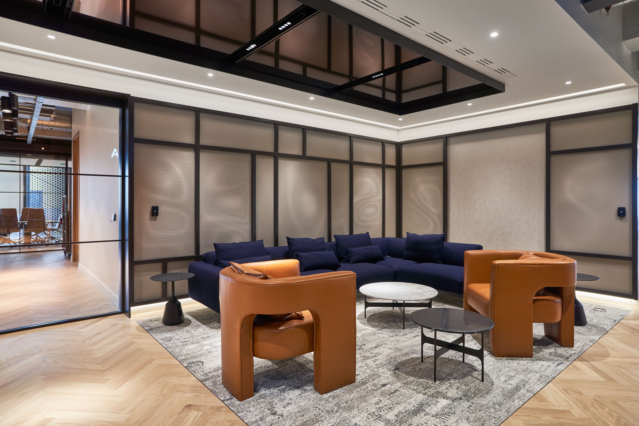 Lounge area at United Talent Agency styled with sculptural leather armchairs, a deep navy modular sofa and minimalist tables, all curated by Platfform.