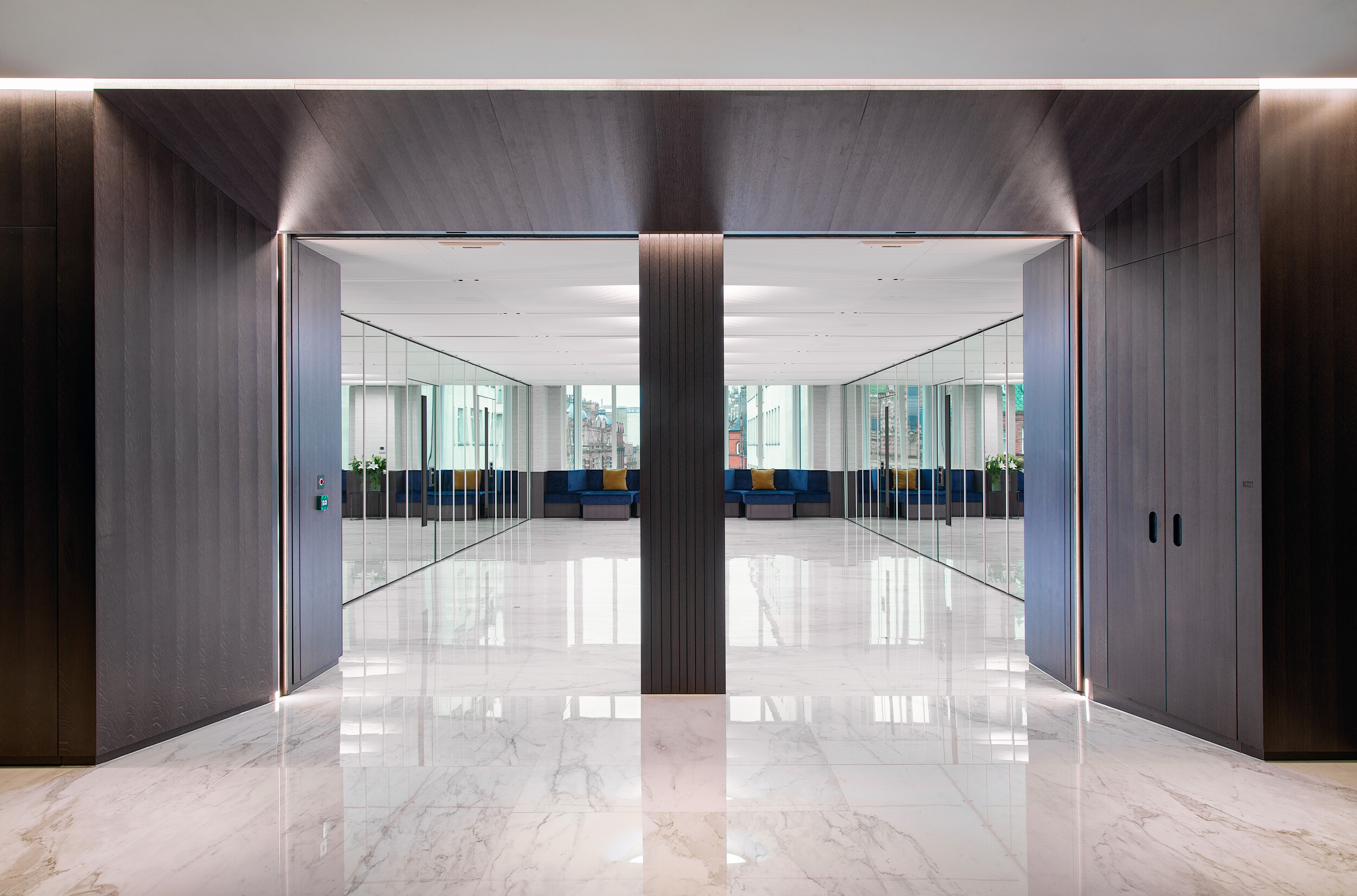 Entrance to Vedanta’s office space with mirrored walls, marble flooring and bespoke bench seating, designed to reflect light and maximise symmetry.