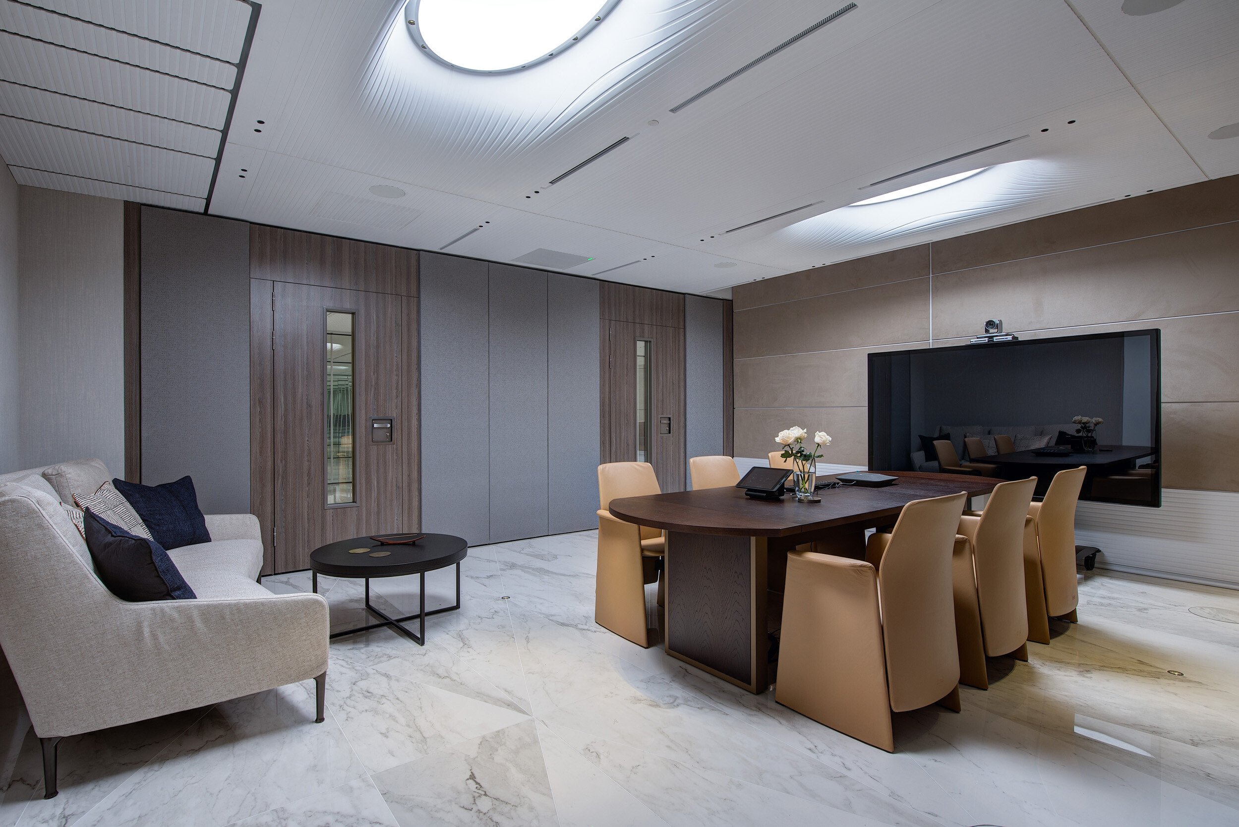 Videoconferencing suite at Vedanta’s London office with tan leather chairs, a soft grey lounge area and integrated tech for hybrid collaboration.
