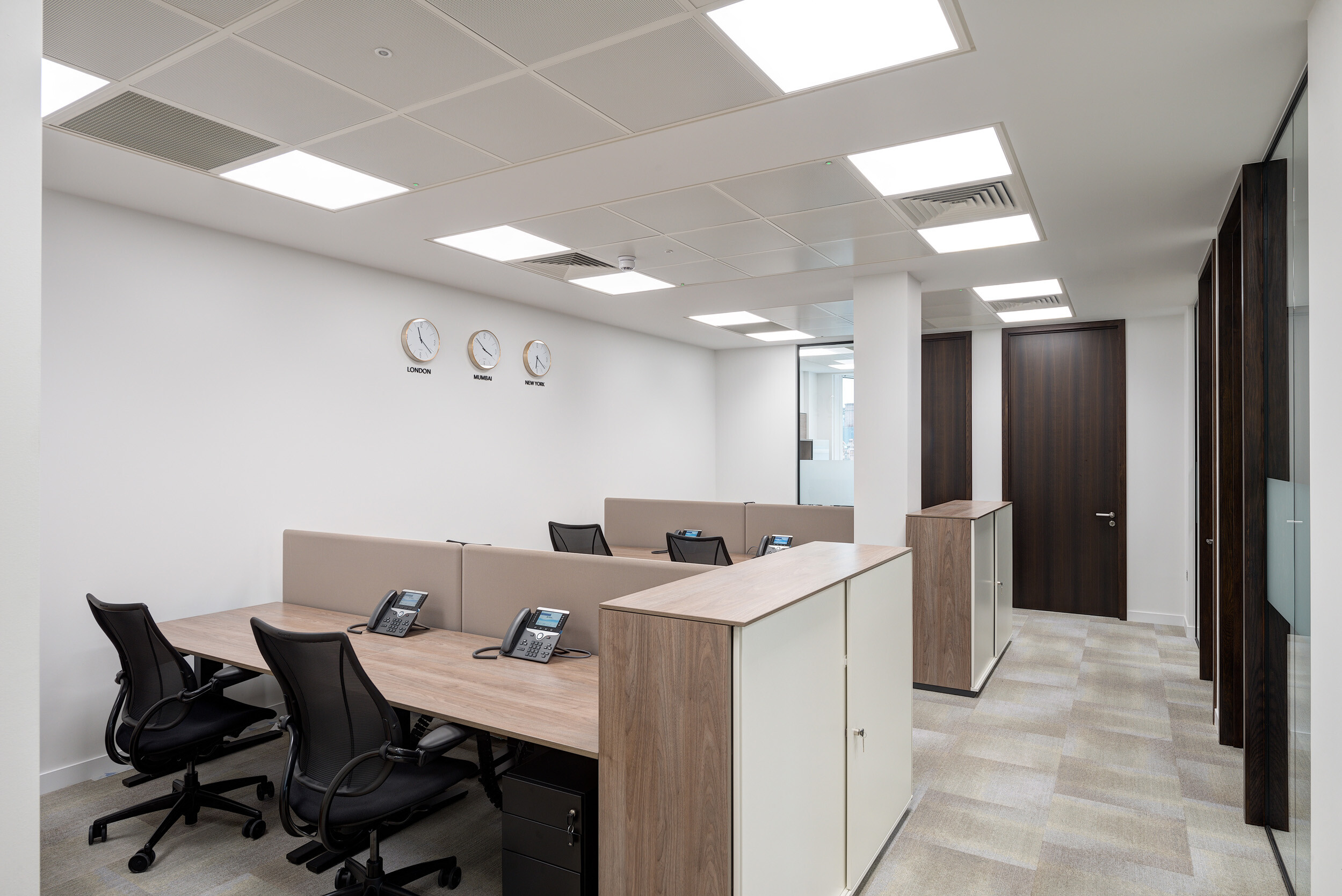 Desking setup at Vedanta’s London office with soft-screen partitions, task chairs and neutral storage, supporting quiet, focused work in a clean layout.