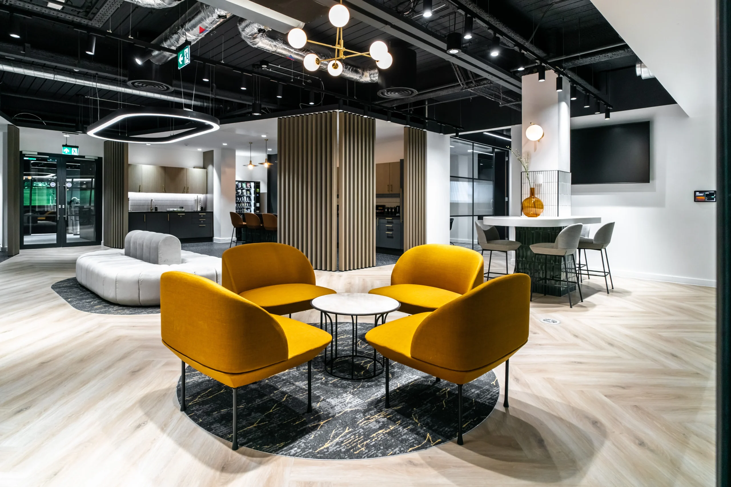 Bold mustard seating and circular rug set the tone for this lounge area at Watches of Switzerland, blending texture and warmth across the space