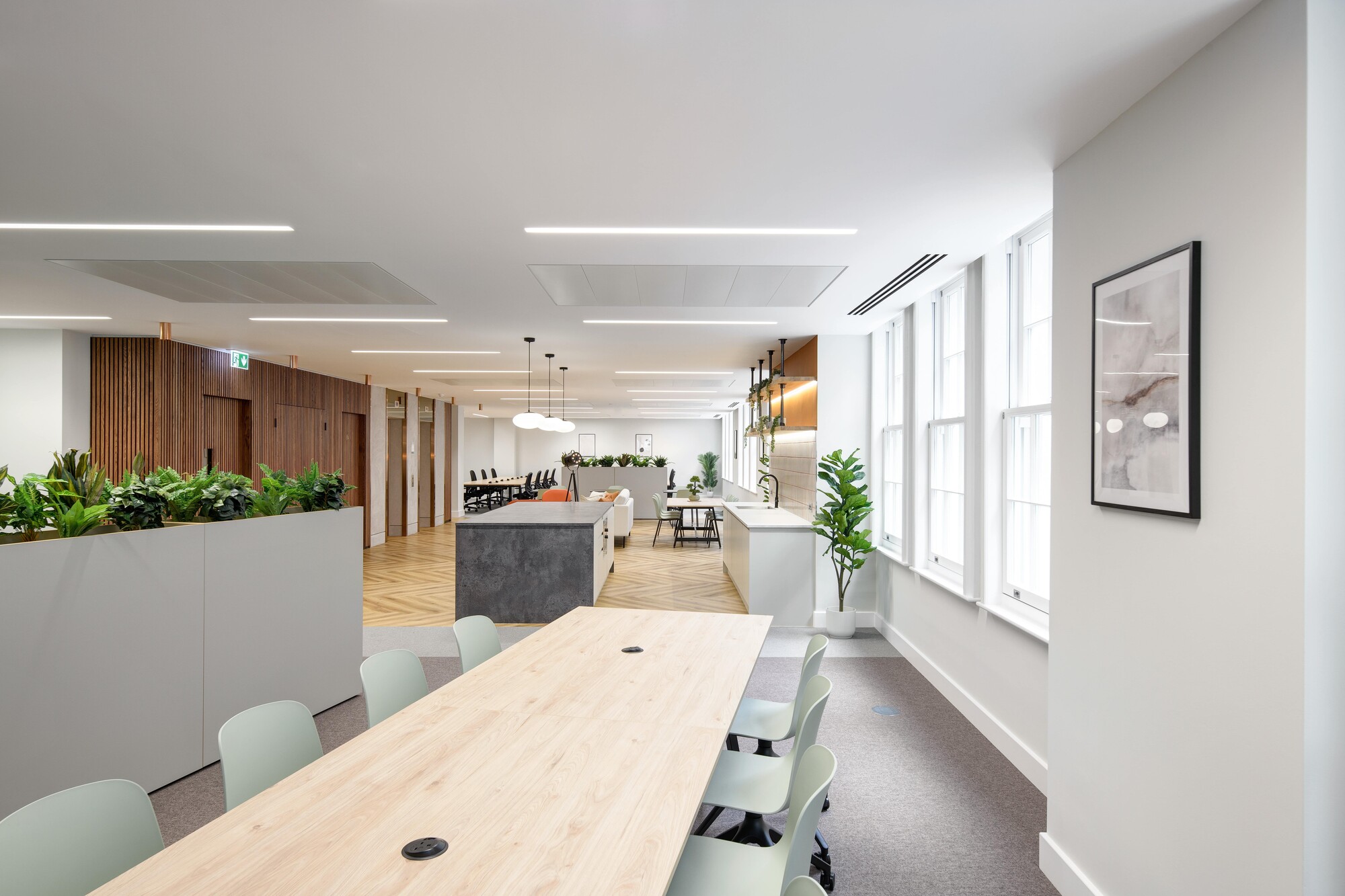 View across an Asset Management Firm's Tenant-Ready™ office, featuring café chairs, meeting tables, and a central island unit, all furnished to support agile working.