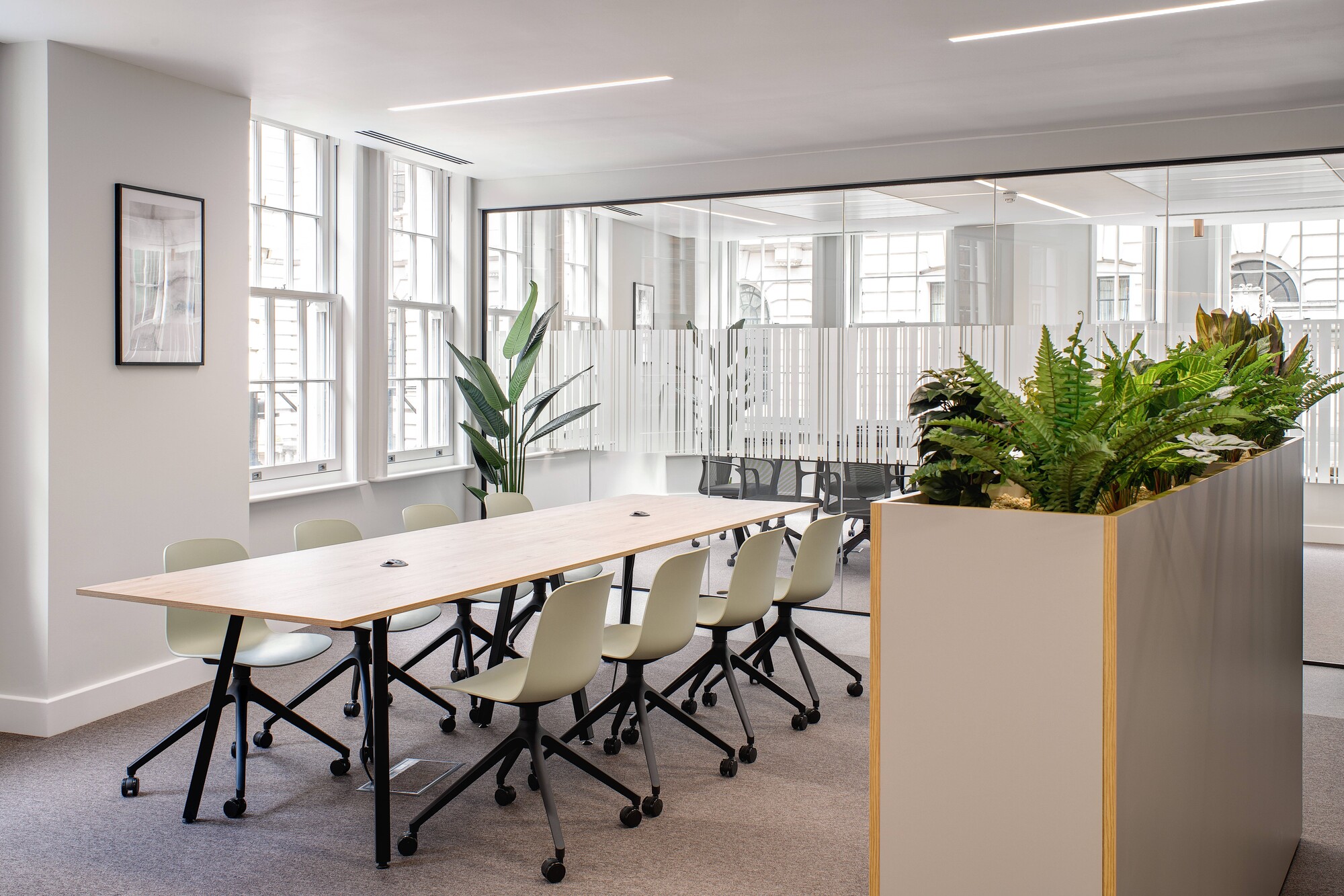 Collaborative workspace for an Asset Management Firm, featuring modular furniture and soft green chairs in a Tenant-Ready™ setting with glazing and integrated biophilia.