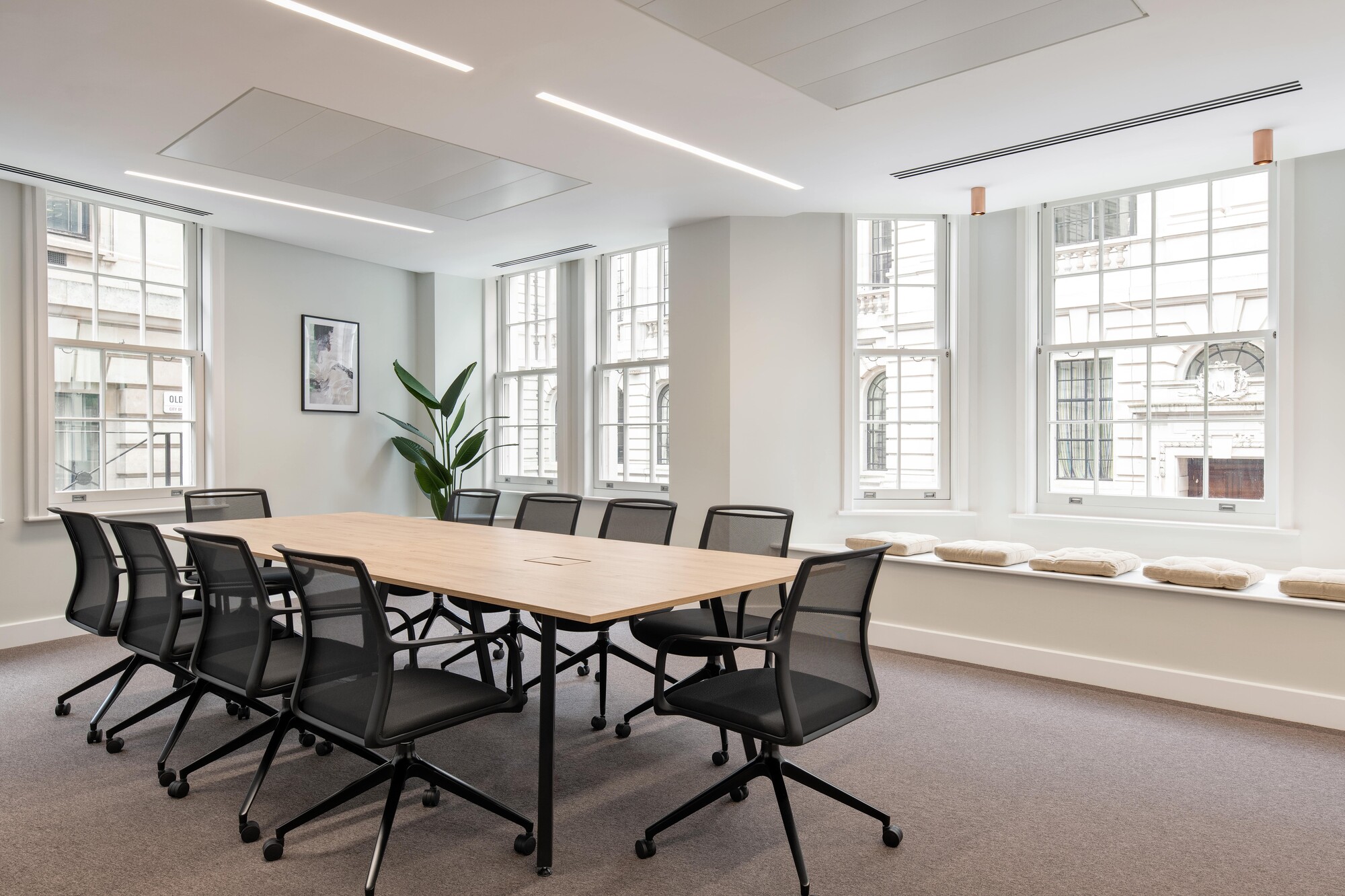 Tenant-Ready™ meeting room for an Asset Management Firm, furnished with mesh-backed chairs, a central table with integrated power, and soft window seating.