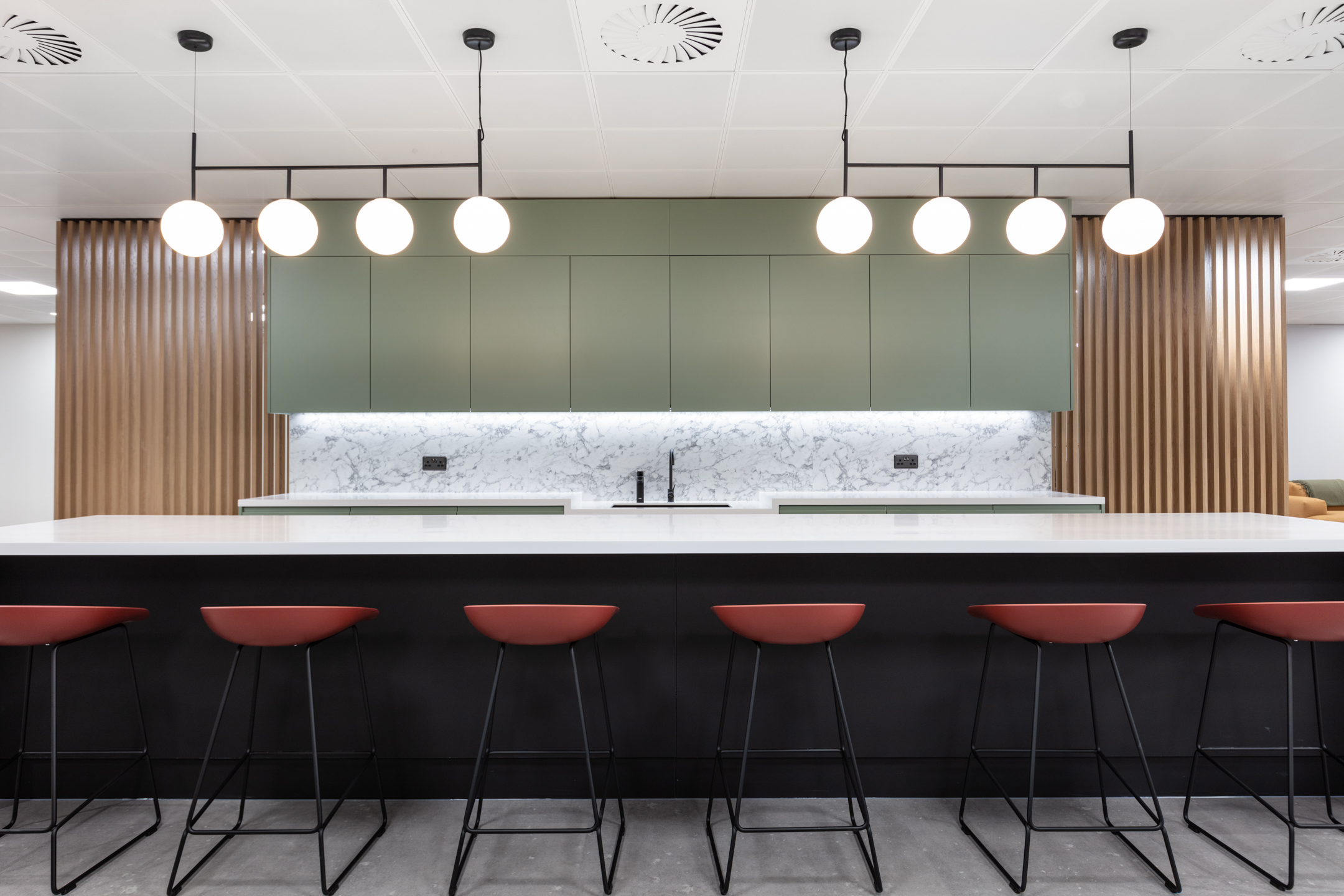 Kitchen island bar at 7 Bishopsgate Level 2 for BGO, furnished by Platfform, featuring integrated counter seating with high stools, positioned within the teapoint to encourage informal interaction.