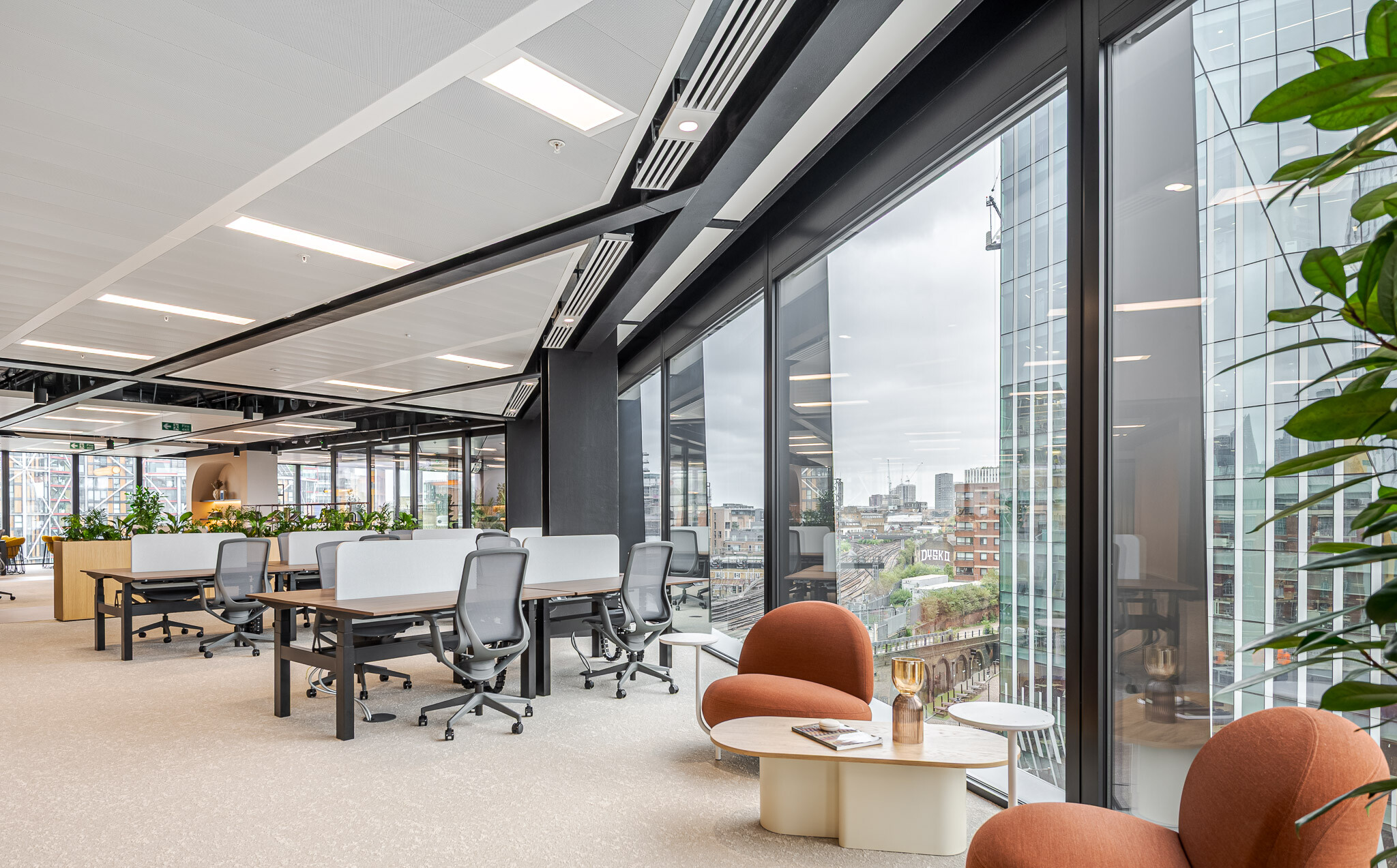 Workspace at Arbor’s Tenant-Ready™ office furnished by Platfform, with shared desks, soft seating by the window, and panoramic views over London’s cityscape and railway.