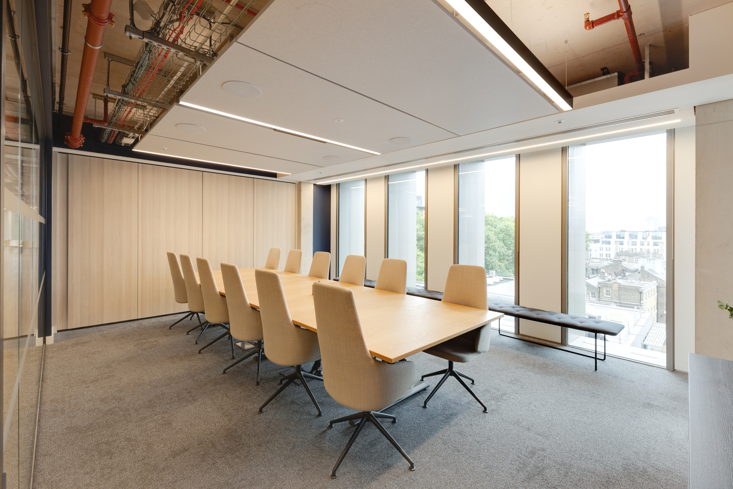 Capital on Tap boardroom with a long wooden meeting table, high-back beige chairs on black frames, and full-height windows bringing in natural light.