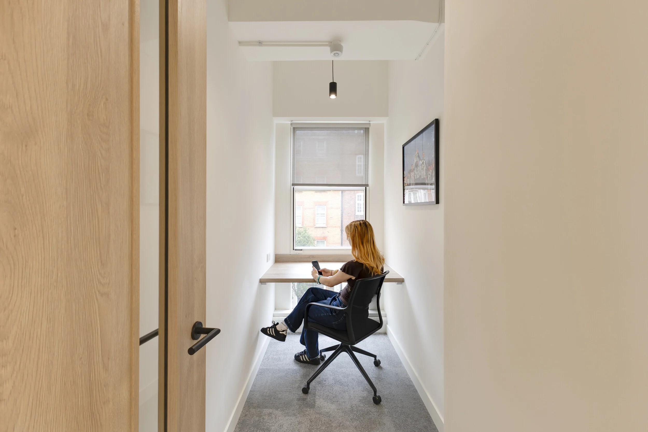 A quiet focus booth at InPost’s London office, furnished by Platfform with a simple desk and black mesh chair. The compact setup makes space for concentrated work beside a bright window.