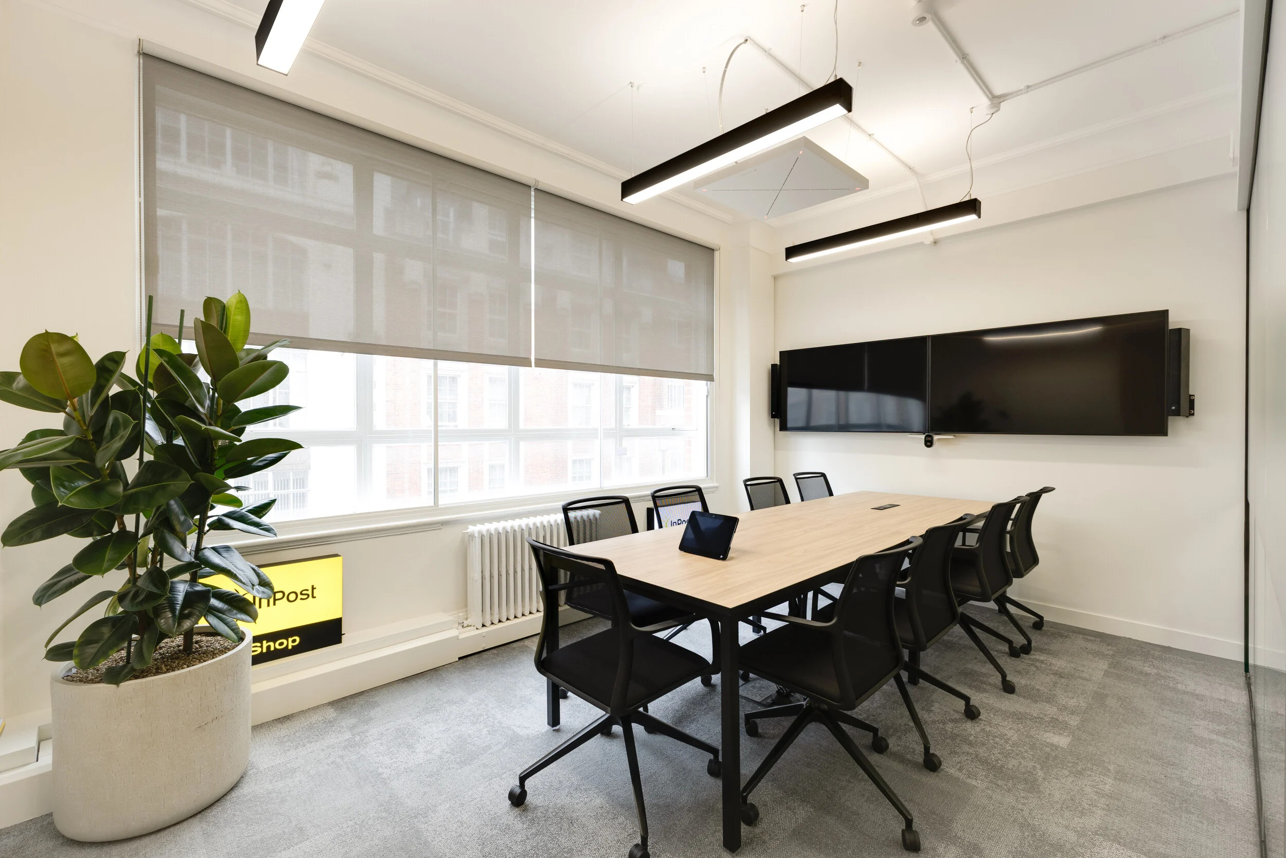 A meeting room at InPost’s London office furnished by Platfform, with a Workstories Co.Stories table in pale oak and black mesh chairs. Large screens and natural light make it a practical space for collaborative discussions.