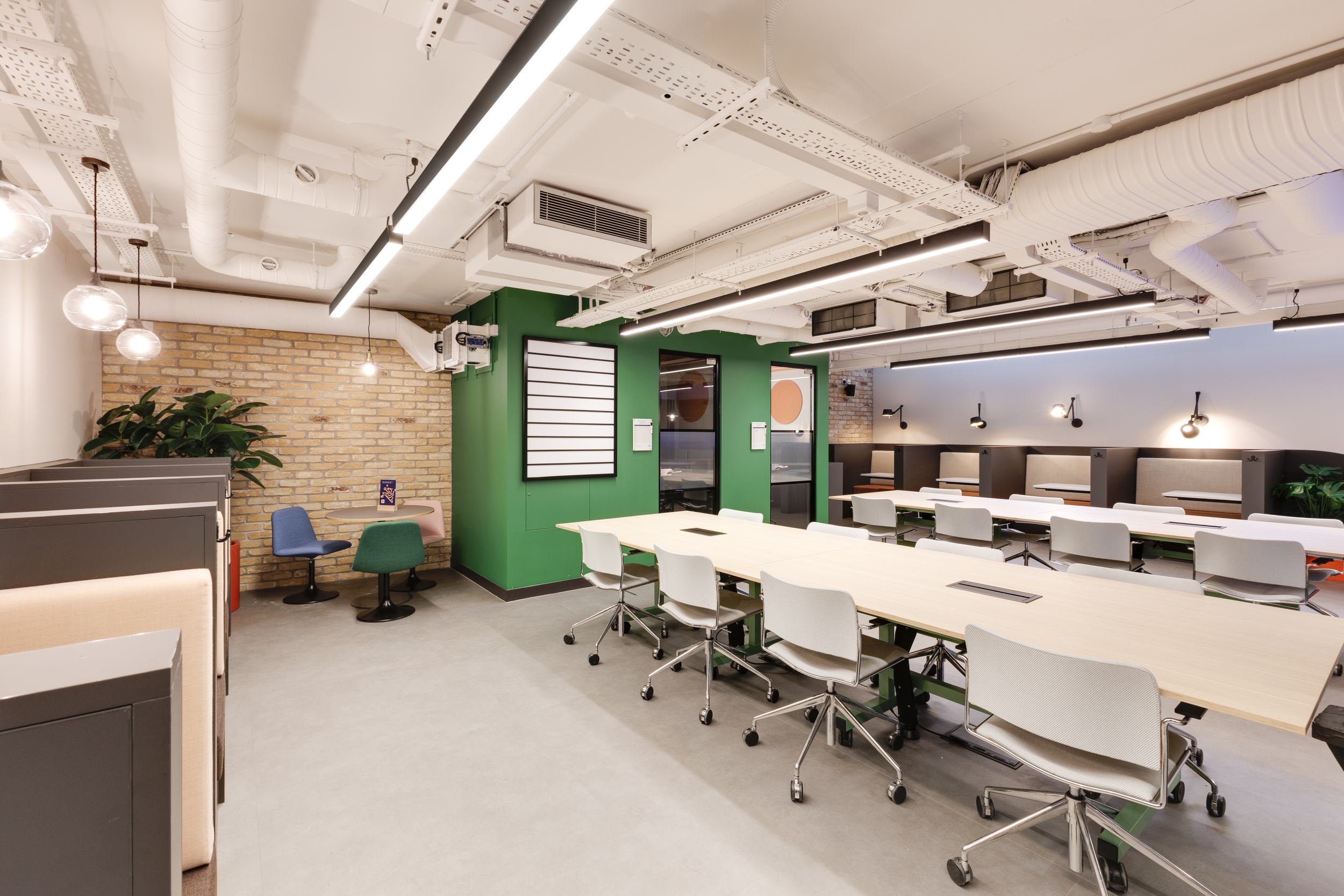 Coworking space at Work.Life Clerkenwell Green with shared desks, green walls, and mixed seating, furnished by Platfform.