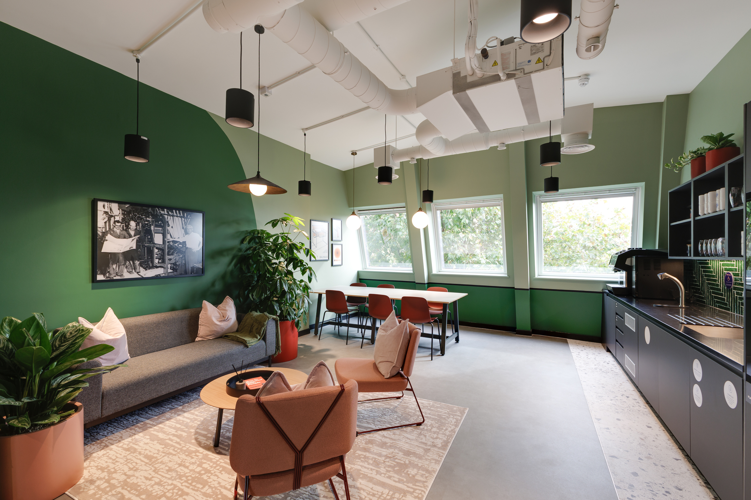 Level 6 teapoint at Work.Life Clerkenwell Green featuring deep green walls, warm-toned furniture and large windows overlooking the trees.