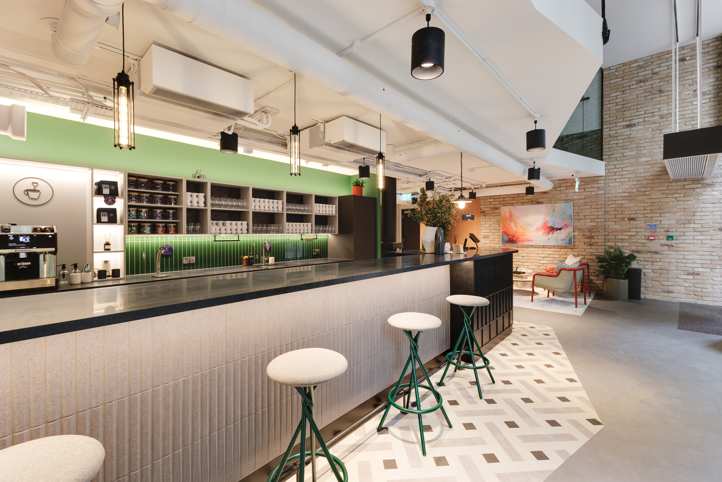 Ground floor teapoint and reception at Work.Life Clerkenwell Green featuring a statement counter with green accents, tiled flooring and contemporary furniture supplied by Platfform.